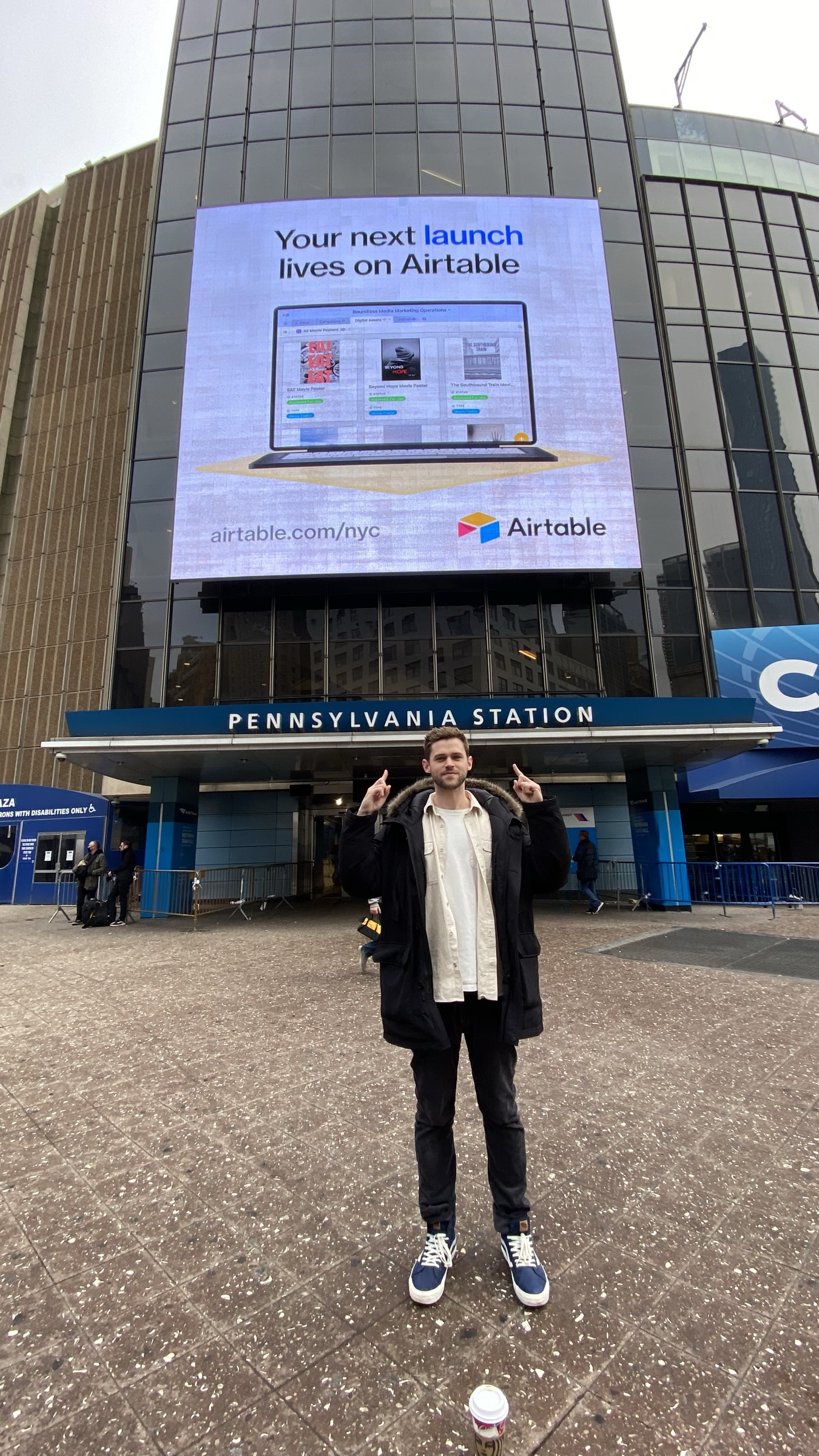 Kevin pointing at Airtable OOH billboard outside Madison Square Garden and Penn Station